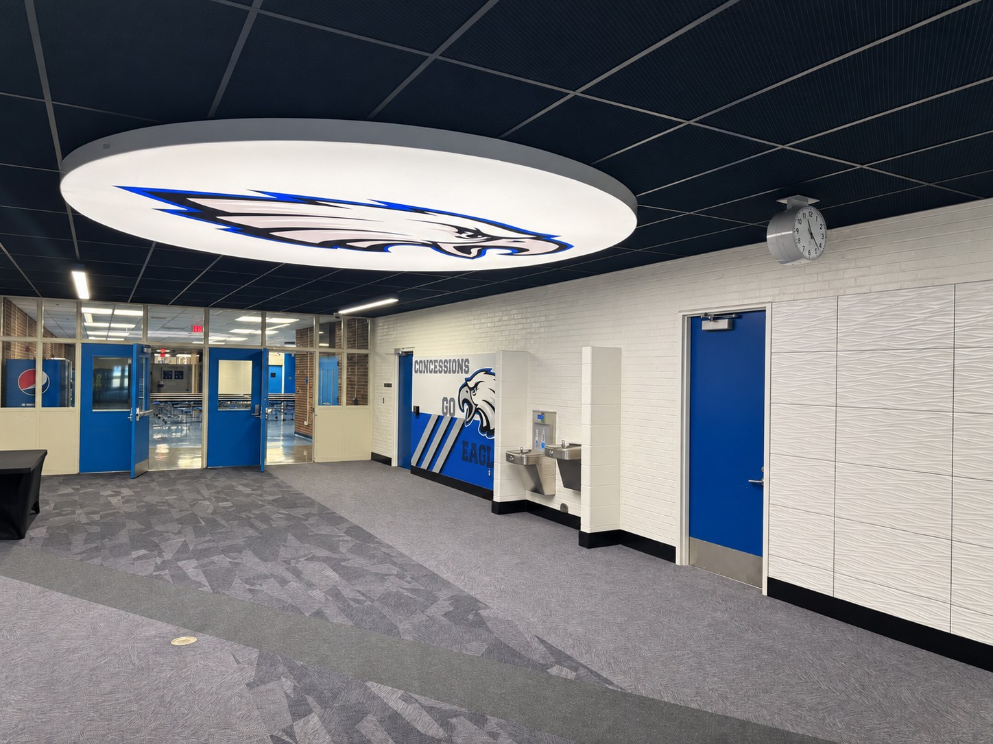 Interior lobby with blue doors, ceiling feature and drinking fountains