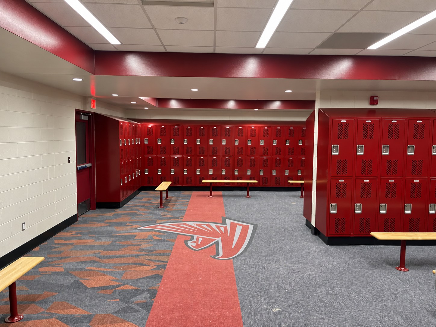 Red lockers, benches and patterned flooring in a locker room